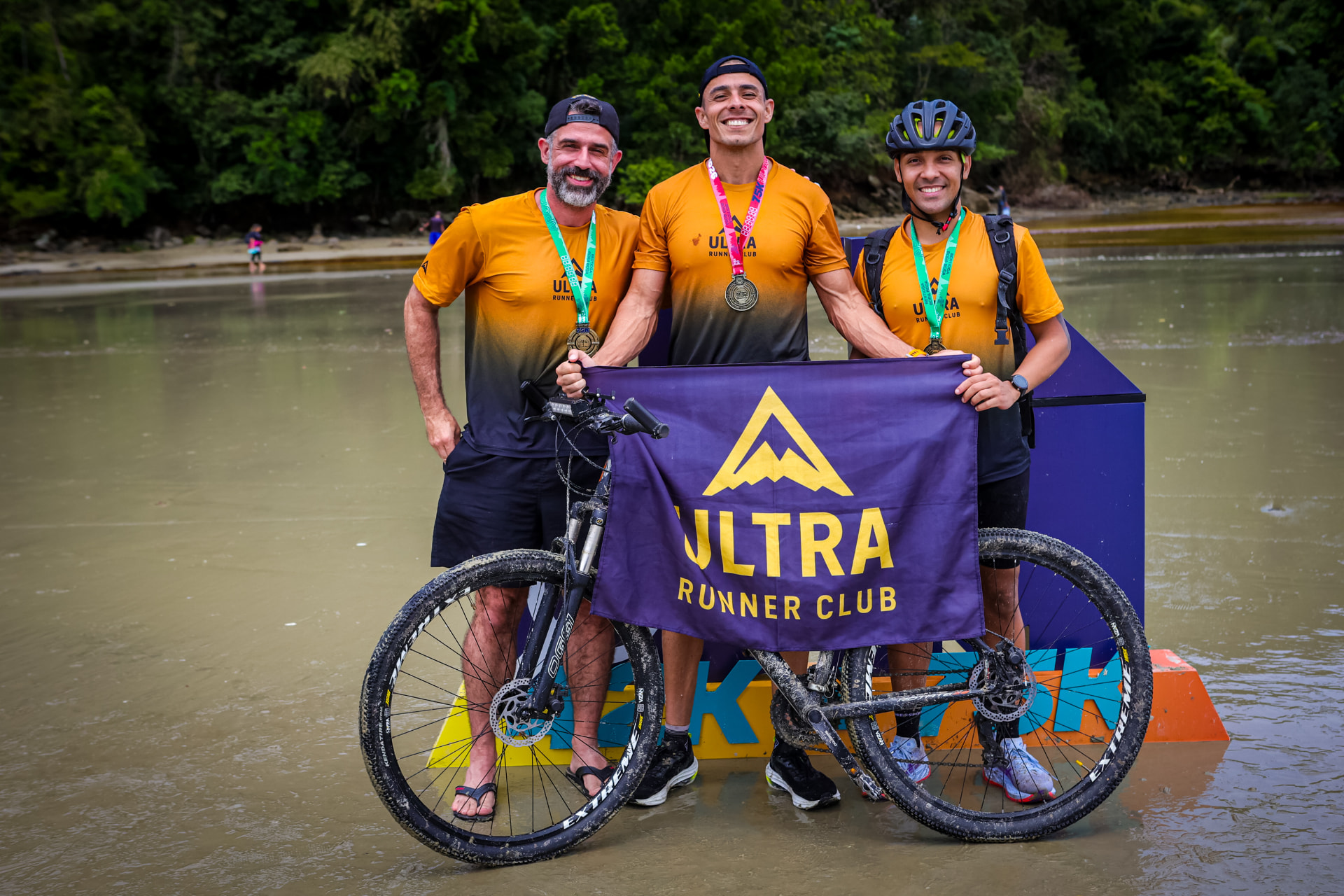 Atletas da Ultra Runner Club com a bandeira do time e medalhas